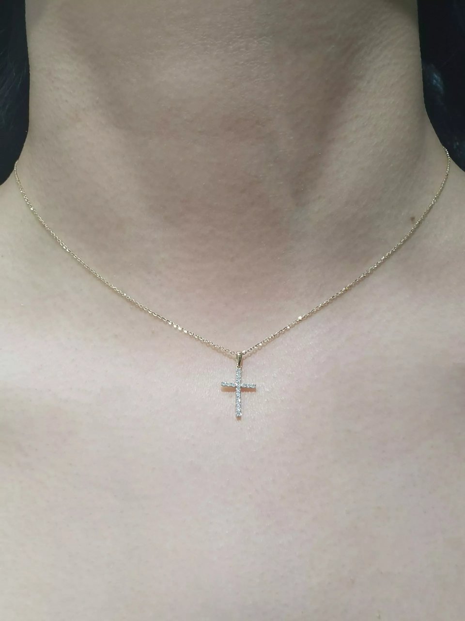 18ct yellow gold claw set 16=0.11ct diamond cross necklace on ladies neck