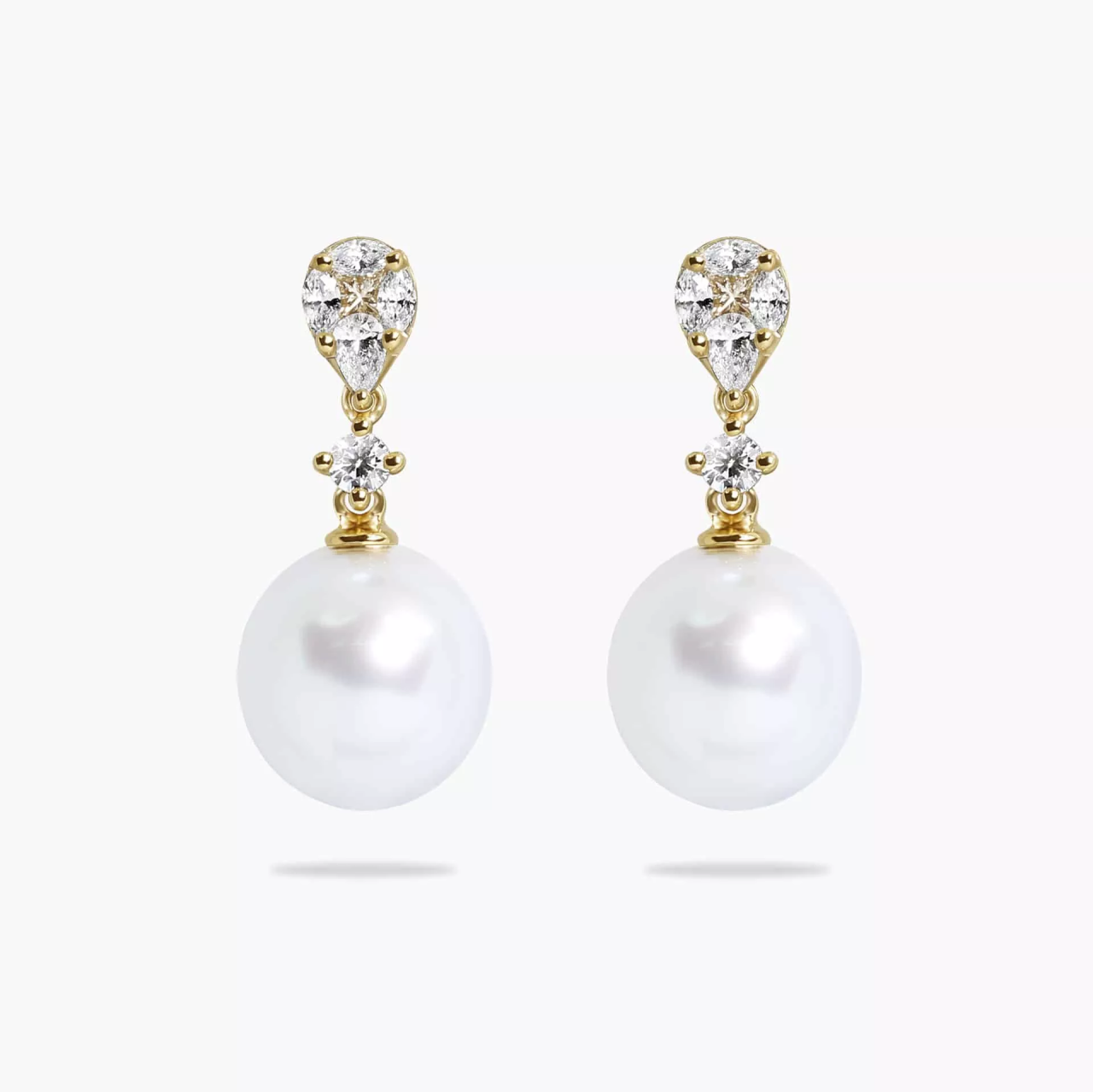 A pair of 18ct yellow gold drop earrings featuring 10mm South Sea pearls and various cuts of diamonds, including marquise, pear, princess, and round brilliant.