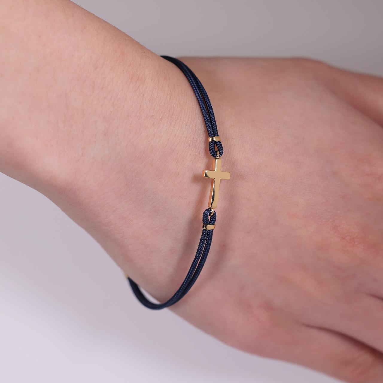 18ct yellow gold cross navy cotton rope bracelet on the wrist