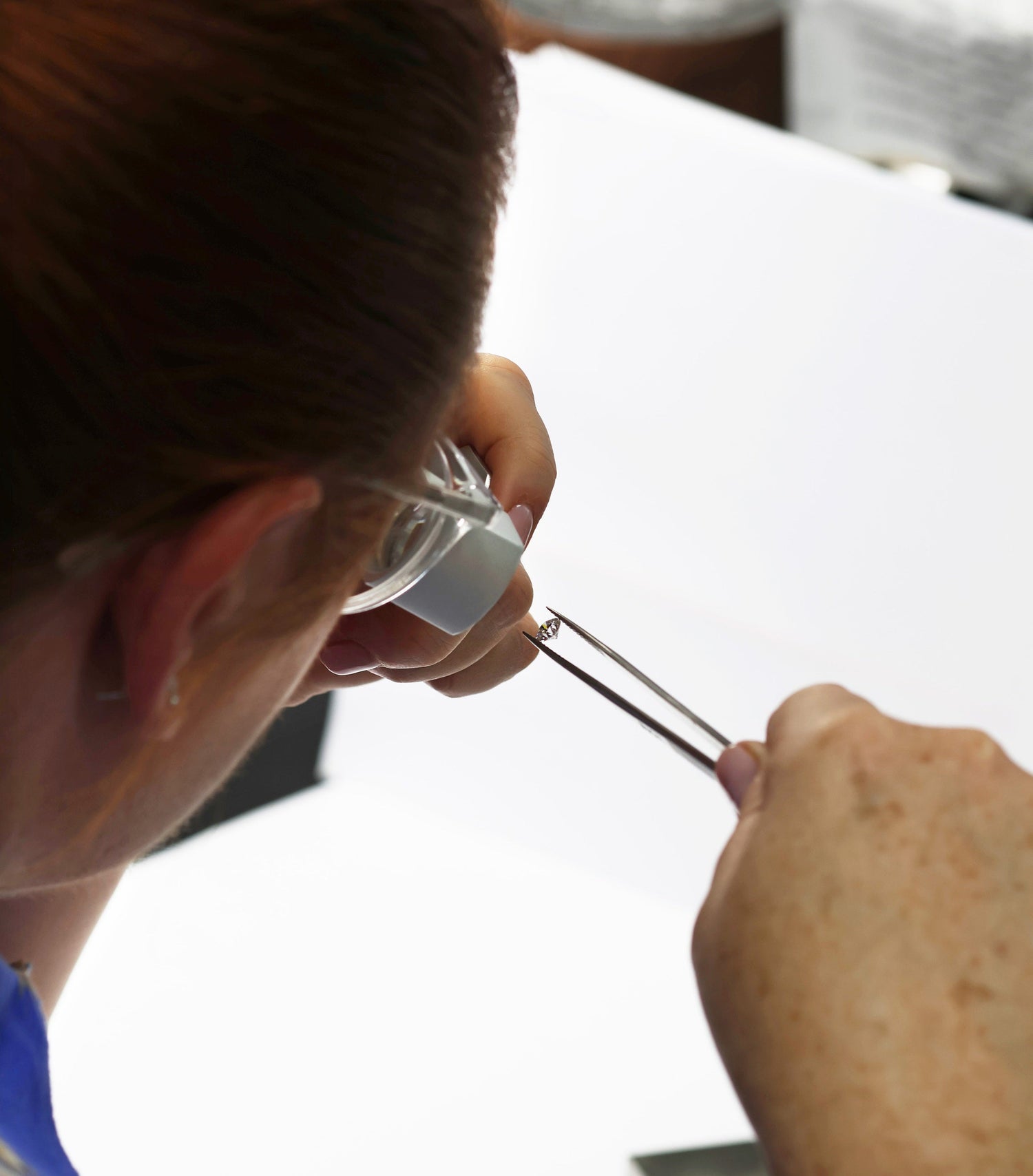 Lady looking through diamond loop assessing a loose diamond