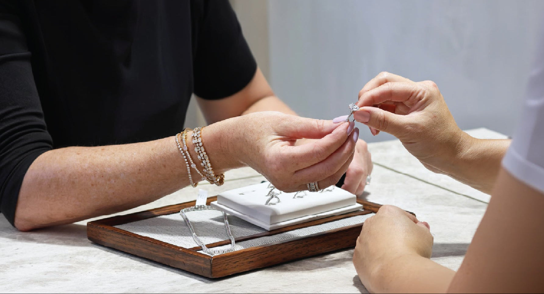 Person examining a ring with another person in a jewelry store setting.