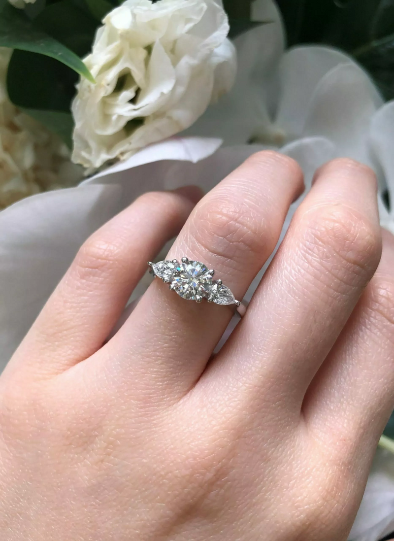 18ct white gold round brilliant and pear cut diamond trilogy ring on finger