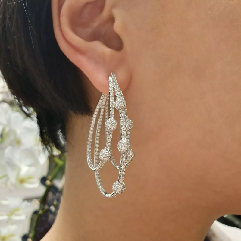 A close-up image of a woman's ear wearing a white gold diamond pave set fancy earring.