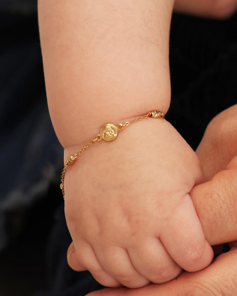 18ct yellow gold baby bracelet with an angel medal on baby wrist