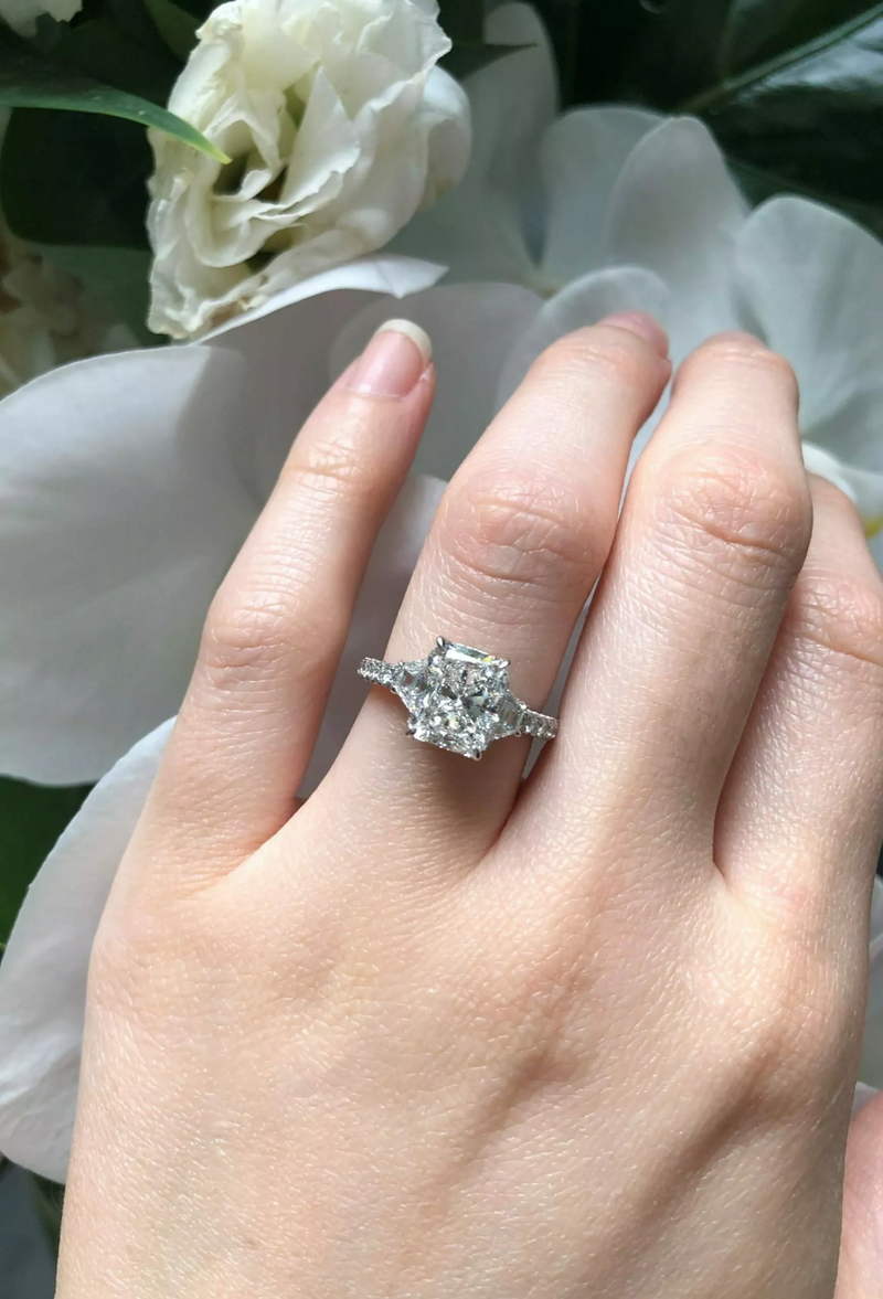 Platinum radiant and trapezoid trilogy round brilliant cut diamond ring on finger