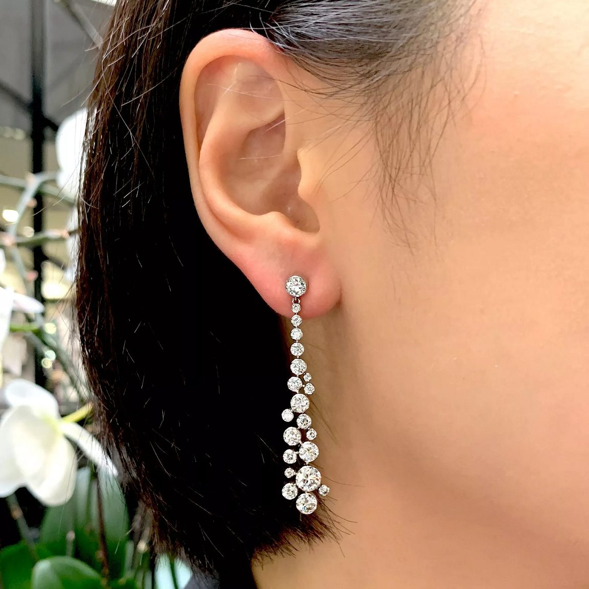 A person wearing platinum diamond drop earrings.