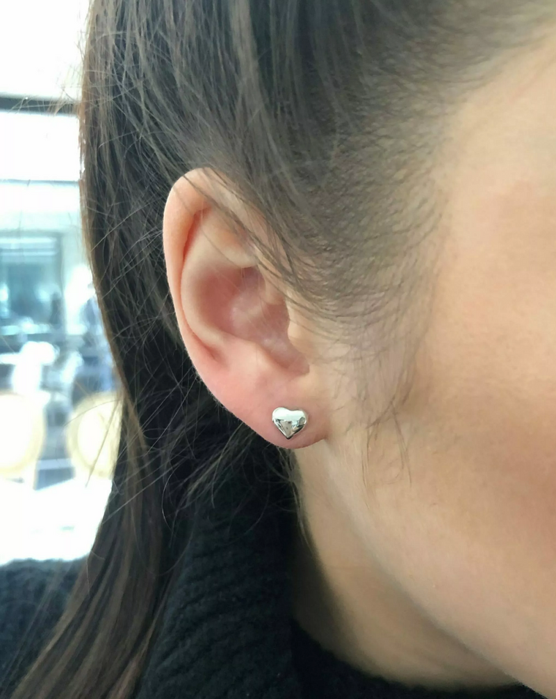 A pair of 18ct white gold baby heart stud earrings on the ear