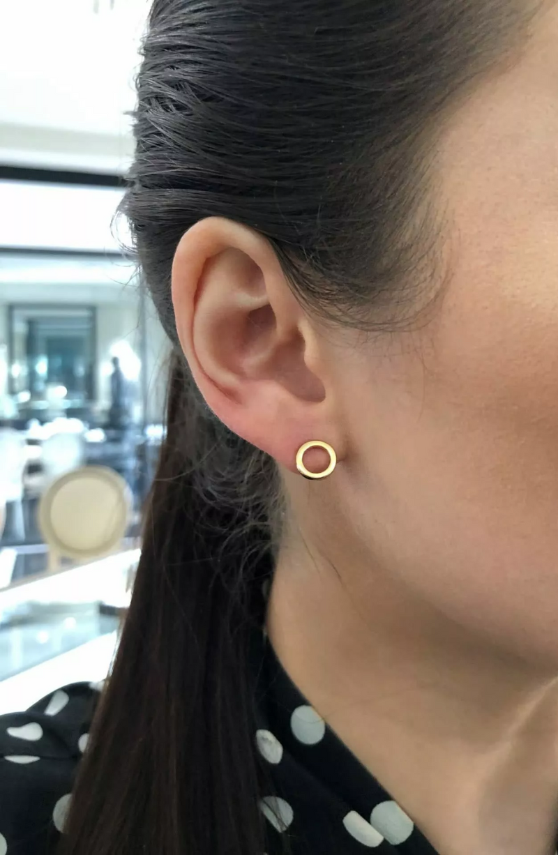 A pair of 18ct yellow gold open circle stud earrings on the ear