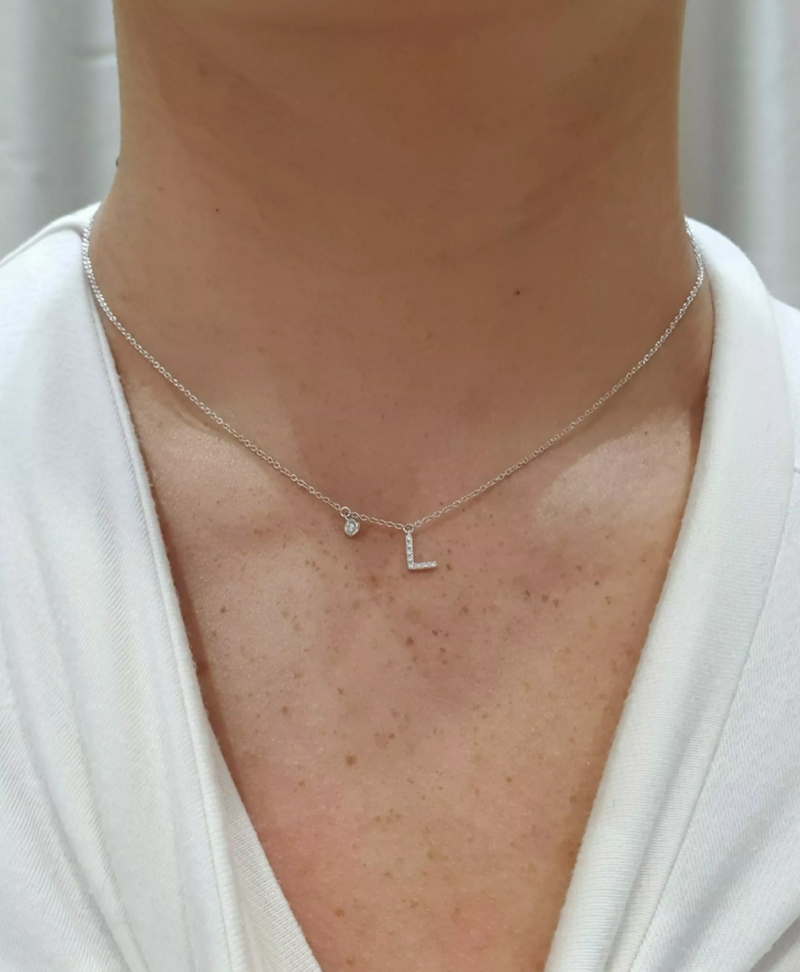 18ct white gold diamond set initial “L” necklace displayed on ladies neck