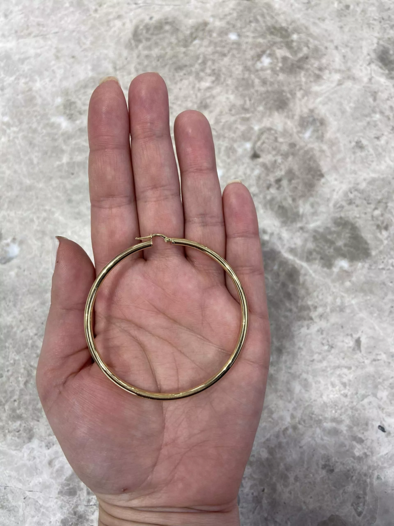 A pair of 18ct yellow gold large hoop earrings with a diameter of 60mm on hand  to show size