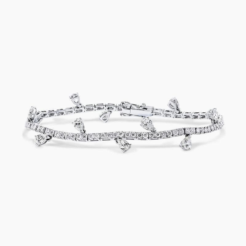 An 18ct white gold diamond tennis bracelet with pear shape diamonds in a claw setting and round brilliant cut diamonds in a four claw setting.