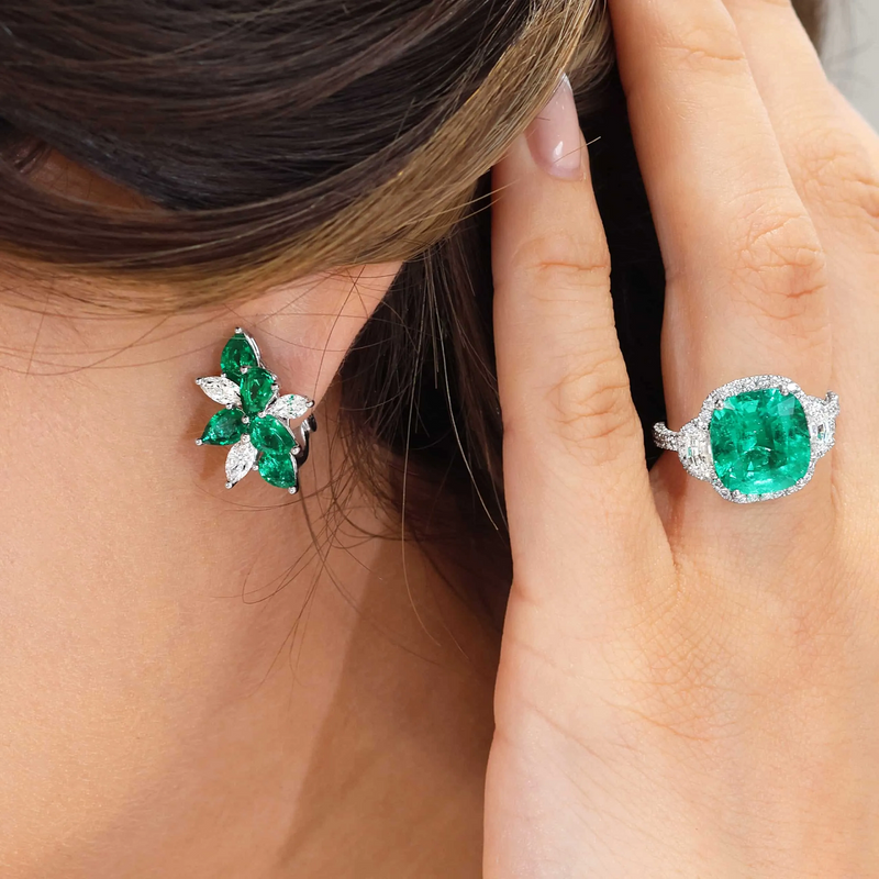 A pair of 18ct white gold earrings featuring pear shape emeralds and diamonds on the ear