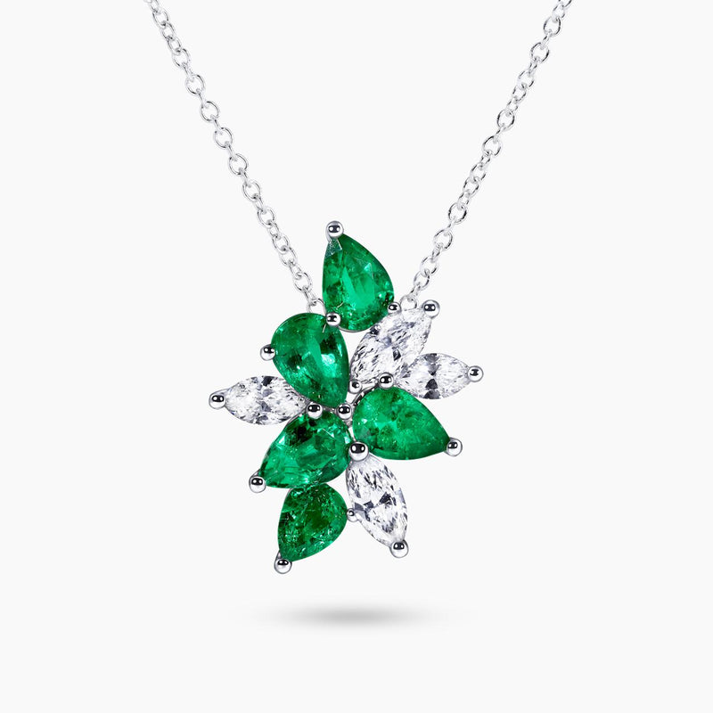 An 18ct white gold pear shape emerald and diamond necklace with a chain and a floral arrangement design featuring green emeralds and white diamonds.