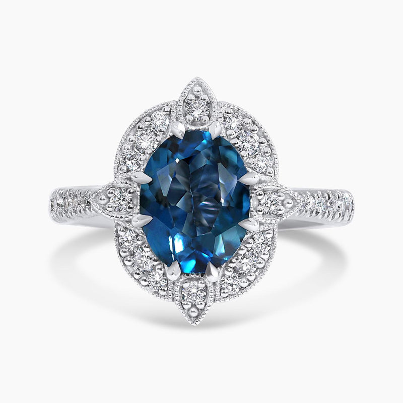 An 18ct white gold ring with an oval London blue topaz centerpiece and a halo of round brilliant cut diamonds.
