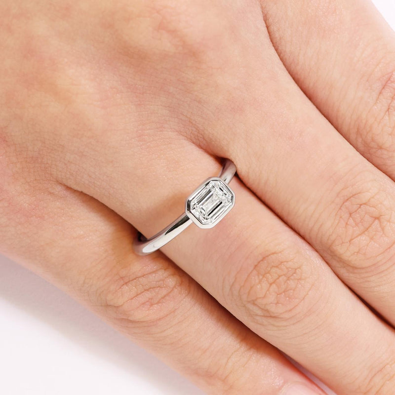 18ct white gold emerald cut bezel set diamond solitaire engagement ring on the finger