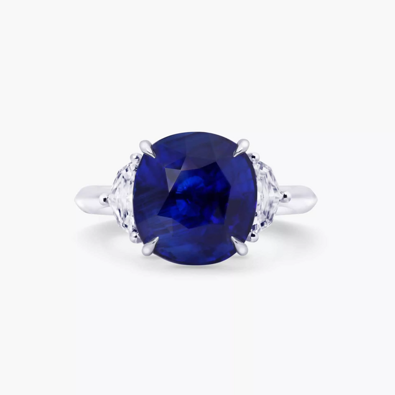 An 18ct white gold cushion cut Ceylon sapphire and cadillac diamond ring with two smaller cushion-cut diamonds on the sides.