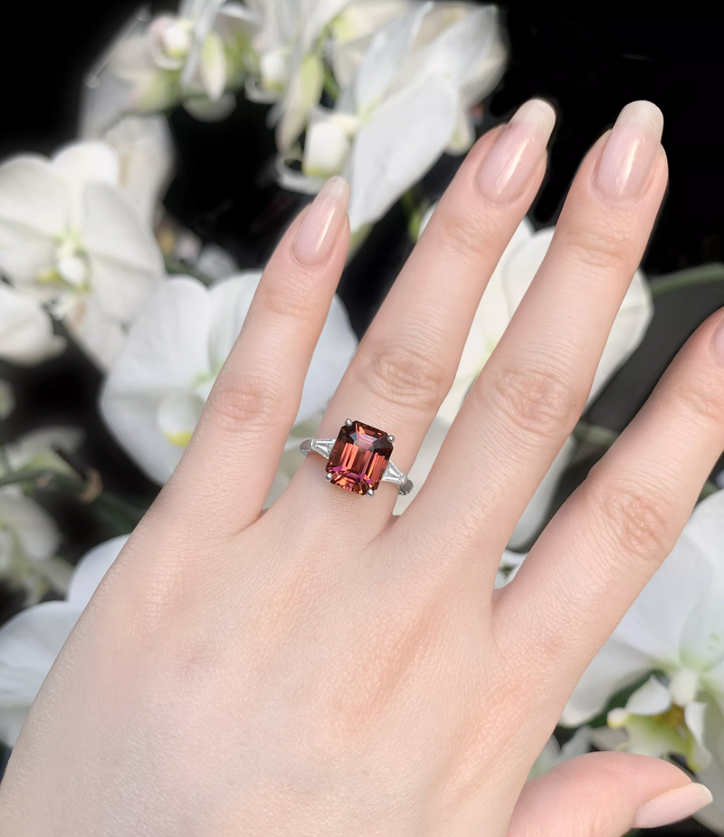 Platinum emerald cut pink tourmaline and tapered baguette diamond ring on the finger