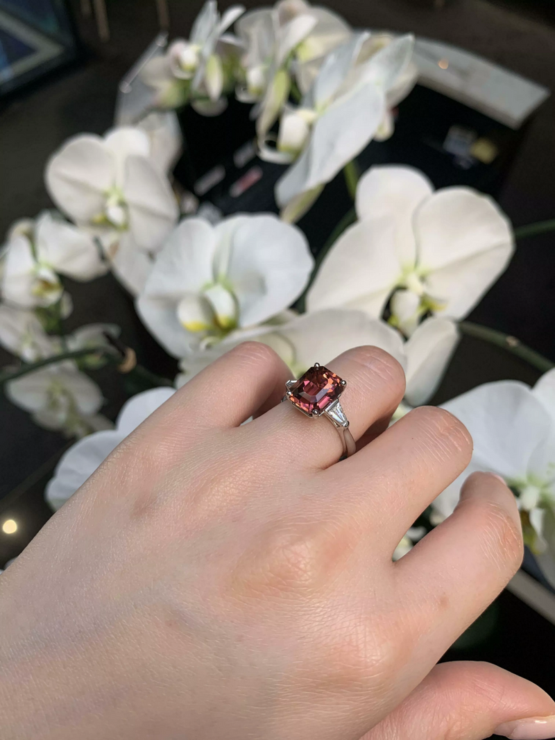 Platinum emerald cut pink tourmaline and tapered baguette diamond ring on the finger