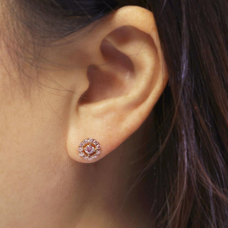 A pair of 18ct rose gold round brilliant cut Argyle pink diamond stud earrings with smaller pink diamonds around the halo on the ear