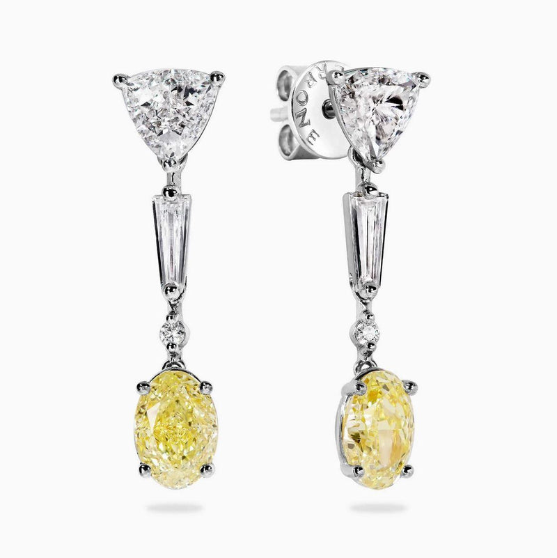 A pair of 18ct white and yellow gold diamond drop earrings featuring fancy yellow oval brilliant cut diamonds, trilliant cut diamonds, tapered baguette diamonds, and round brilliant cut diamonds.