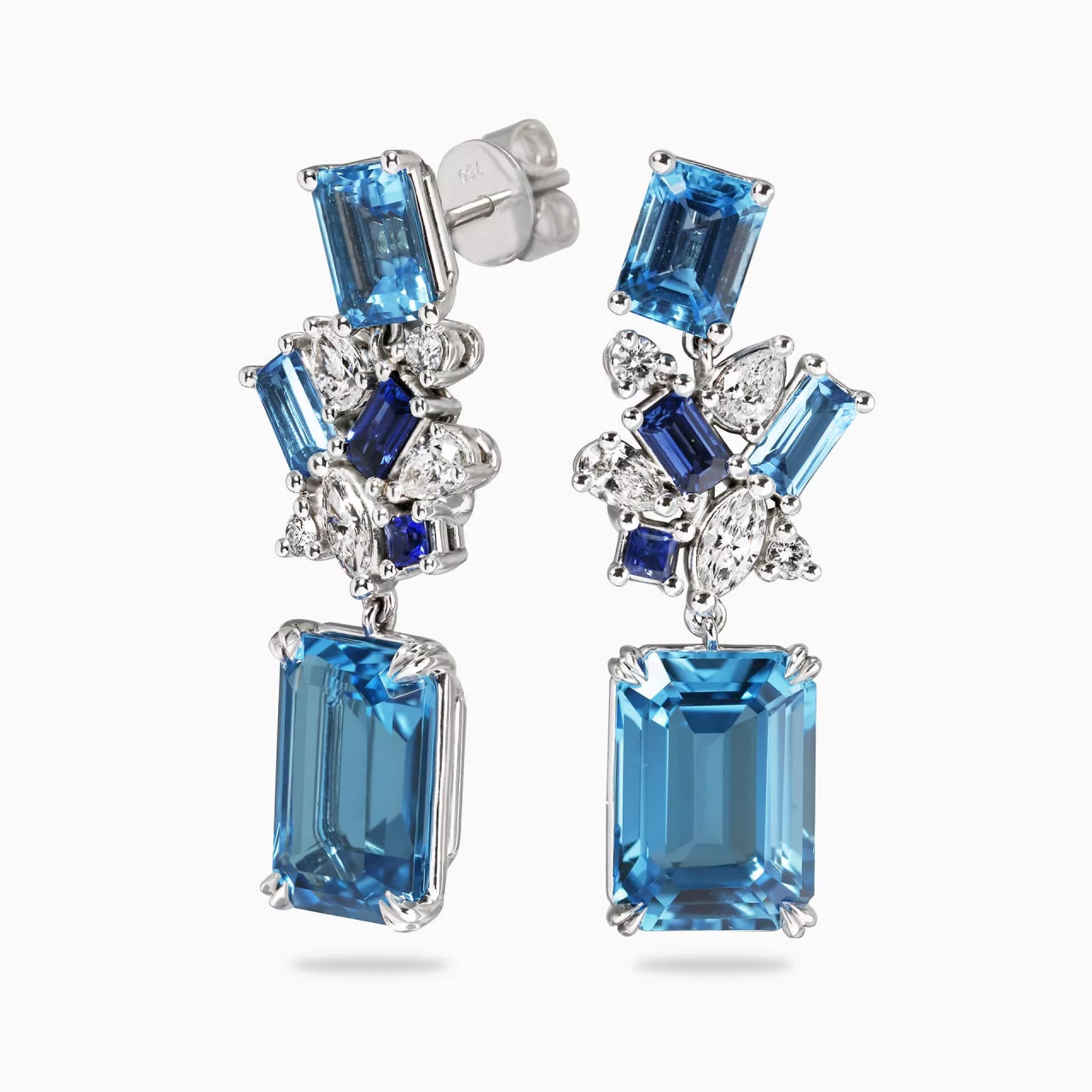 A pair of 18ct white gold drop earrings featuring emerald cut Swiss blue topaz, baguette Swiss blue topaz, princess cut Ceylon sapphire, baguette Ceylon sapphire, pear shaped diamonds, round brilliant cut diamonds, and marquise diamonds.