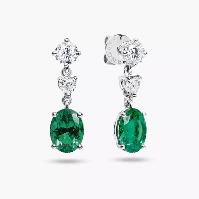 A pair of 18ct white gold drop earrings featuring oval shape emeralds and round brilliant cut diamonds.