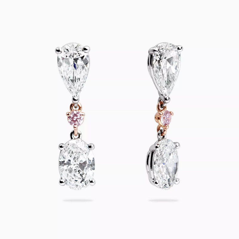 A pair of 18ct white and rose gold drop earrings featuring oval and pear shaped Australian pink diamonds with round brilliant cut diamonds in a claw setting.