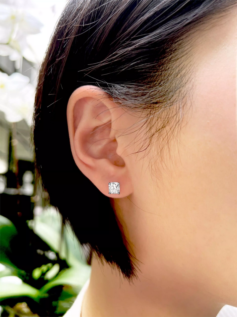 A pair of 18ct white gold cushion cut diamond stud earrings with a four claw setting on the ear