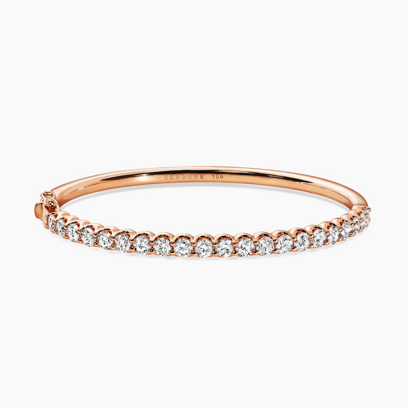 An 18ct rose gold claw set diamond hinged bangle with multiple round brilliant cut diamonds.