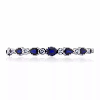 An 18ct white gold diamond and sapphire bangle with pear-shaped blue sapphires and round brilliant cut diamonds.