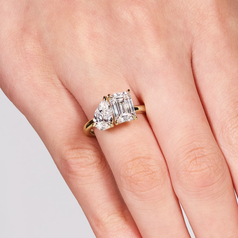 18ct yellow gold emerald and pear cut lab grown diamond ring on finger