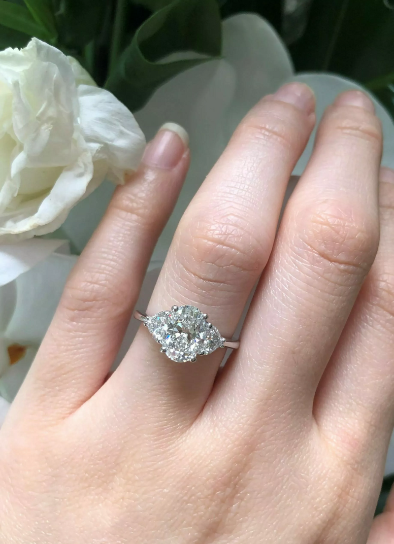 18ct white gold oval and heart shaped diamond trilogy ring on finger