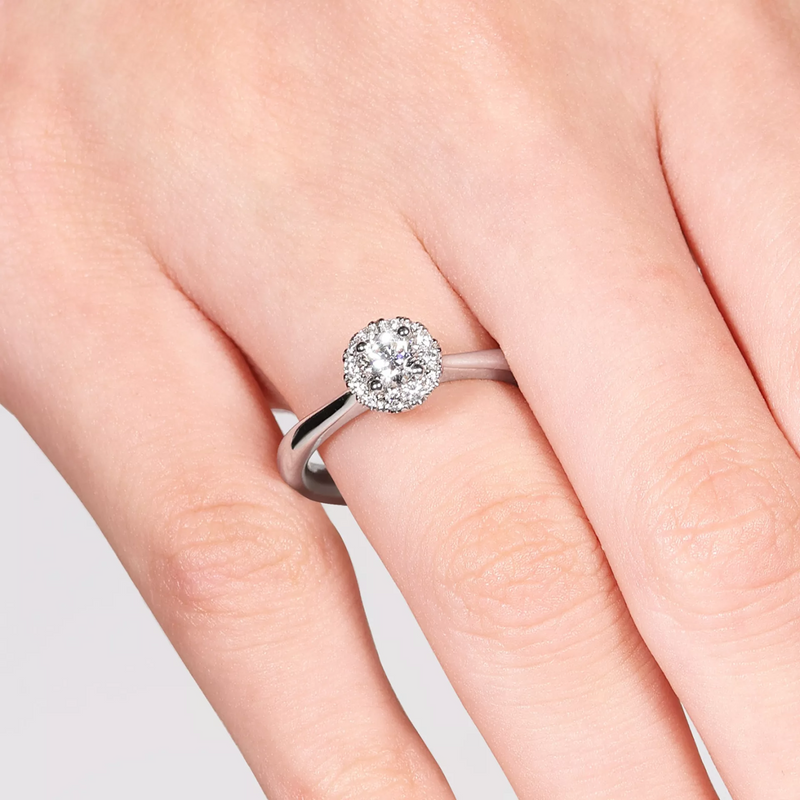 Platinum 0.30ct G SI1 round brilliant cut diamond halo ring on finger