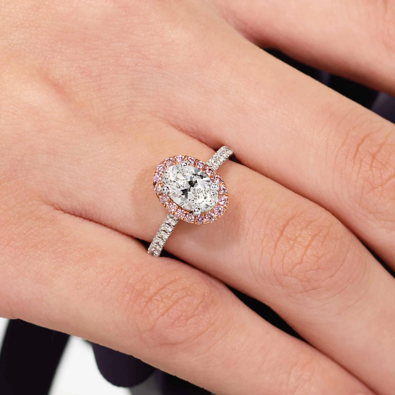 18ct rose and white gold oval and round brilliant cut diamond halo ring on finger