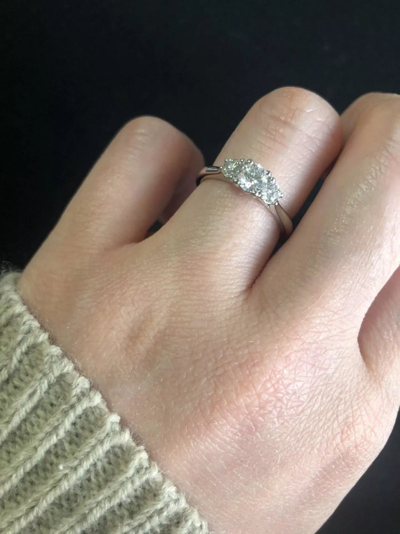 Platinum round brilliant cut diamond trilogy ring on finger