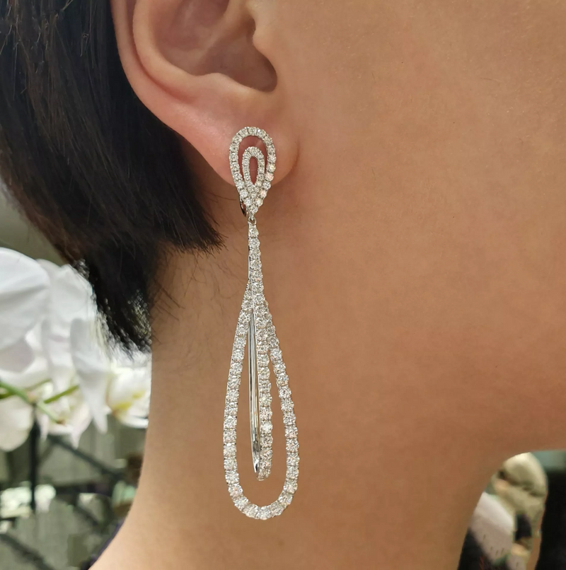 A close-up image of a woman's ear wearing a white gold diamond claw set drop earring.