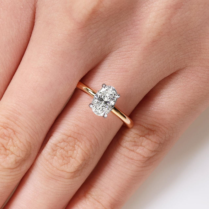 18ct rose and white gold oval brilliant cut diamond with round brilliant cut diamond hidden halo on finger