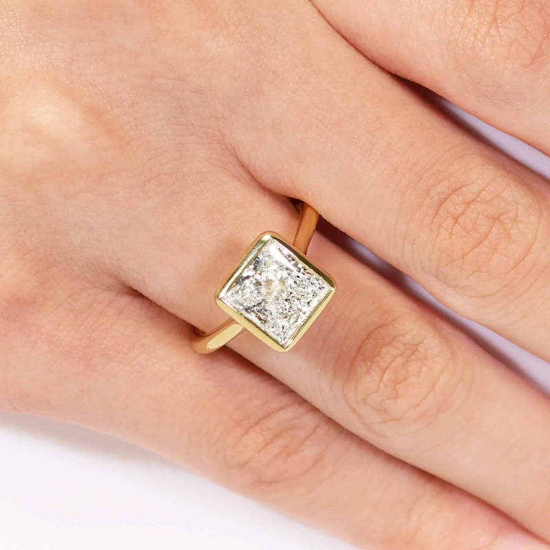 18ct yellow gold princess cut bezel set upswept diamond ring on finger