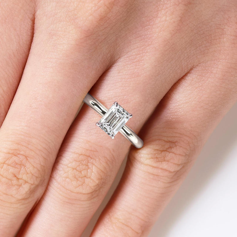18ct white gold emerald cut diamond solitaire engagement ring in a four claw setting on the finger