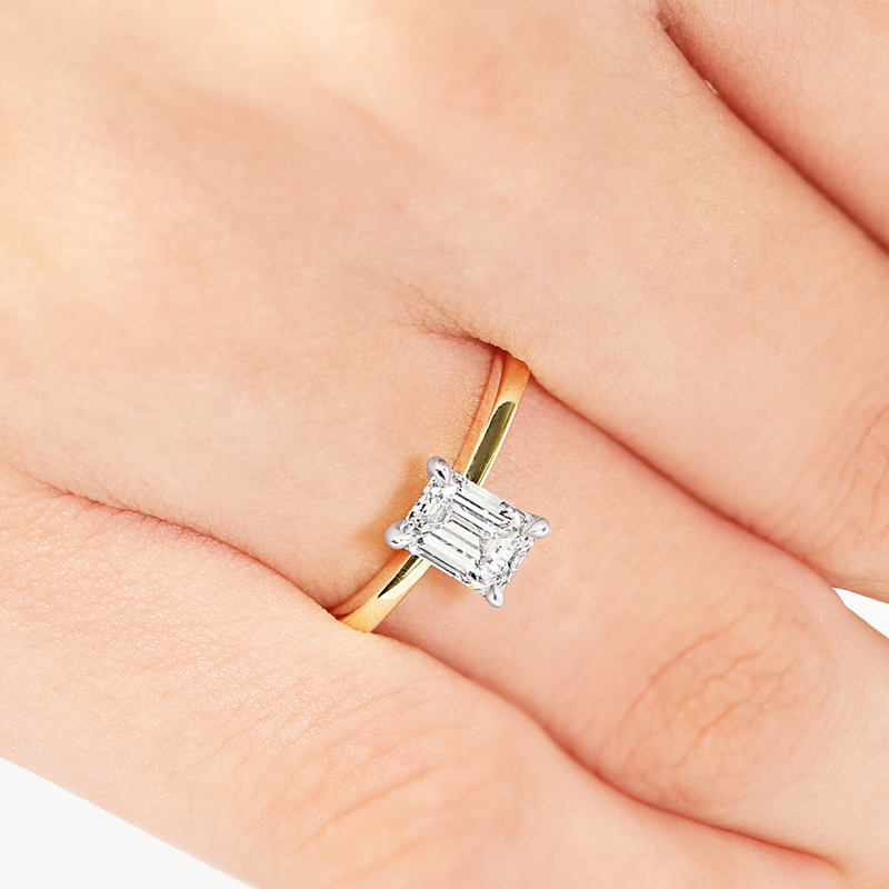 18ct yellow and white gold emerald cut diamond solitaire ring on finger