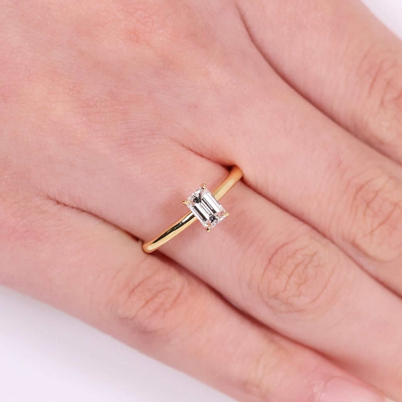 18ct yellow gold 0.50ct emerald cut solitaire ring in a four claw setting on the finger