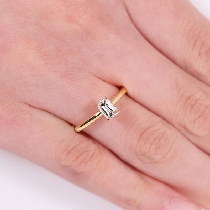 18ct yellow gold 0.50ct emerald cut solitaire ring in a four claw setting on the finger