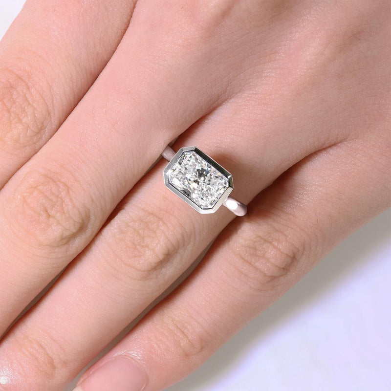 18ct white gold elongated radiant cut lab grown diamond bezel set solitaire ring on finger