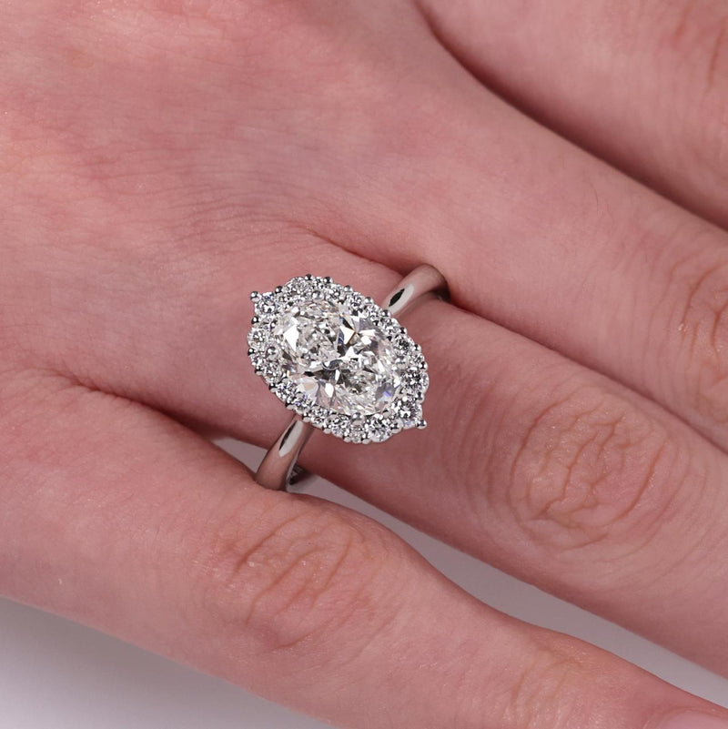 18ct white gold 2.00ct oval cut lab grown diamond halo ring on finger