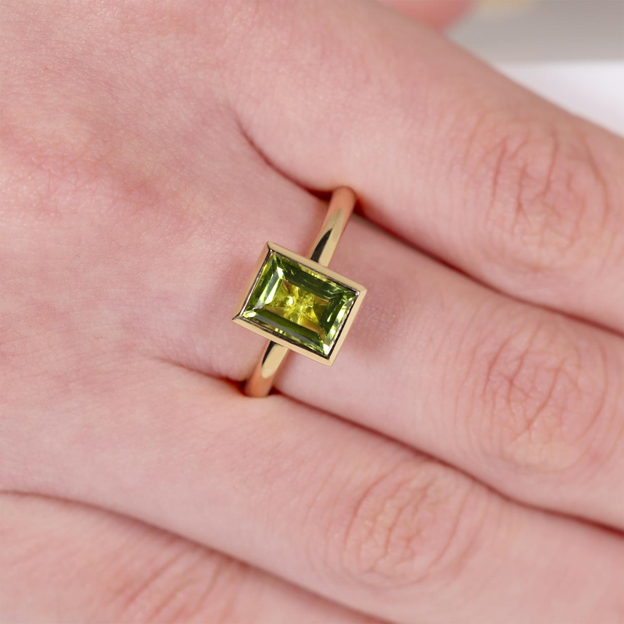 18ct yellow gold 1.90ct baguette peridot ring in a bezel setting on the finger