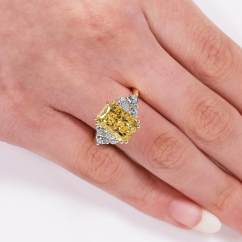 18ct yellow gold fancy vivid yellow radiant cut lab grown diamond pear and round brilliant cut diamond engagement ring on the finger