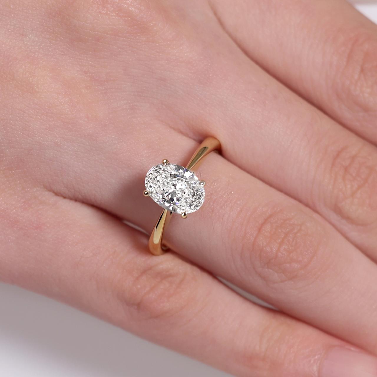 18ct yellow gold oval diamond ring in a four claw setting with hidden halo on the finger