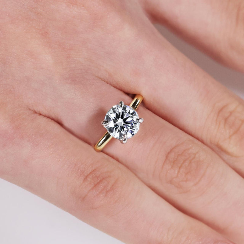 18ct yellow and white gold round brilliant cut diamond four claw solitaire ring on finger