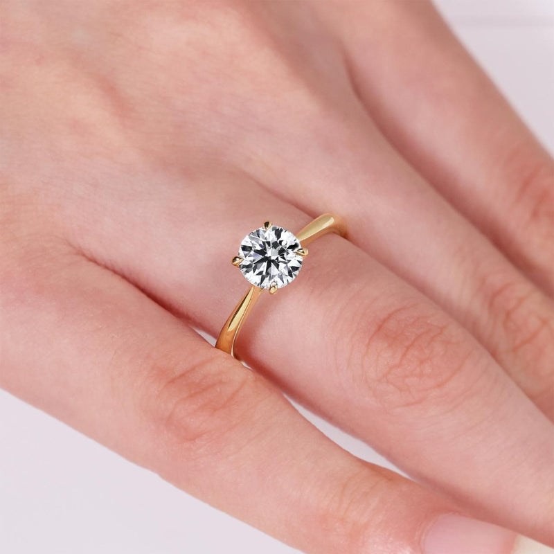 18ct yellow gold round brilliant cut diamond four claw solitaire ring on finger