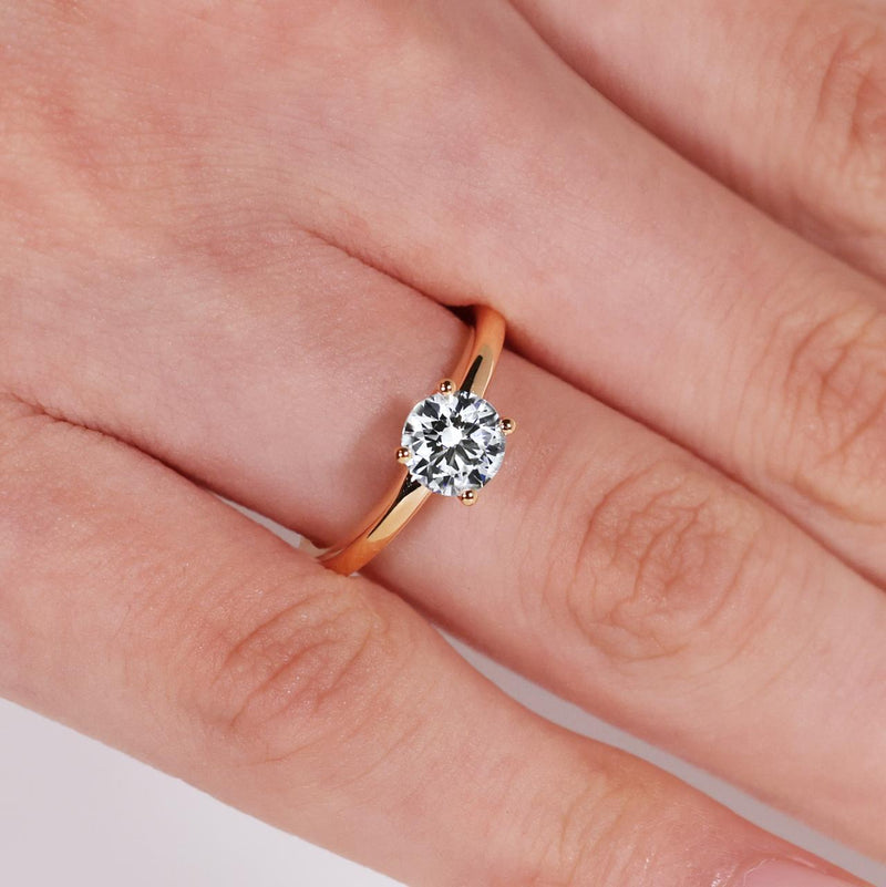 18ct rose gold round brilliant cut diamond four claw solitaire ring on finger